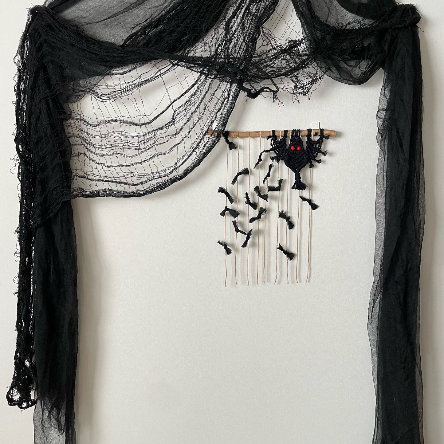 "Imminent" Bats Macramé Wall Hanging on white wall with Hlloween drapings