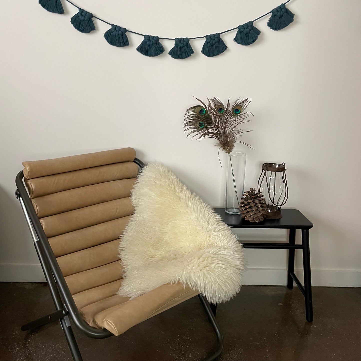 Peacock Festive Garland hung on wall with chair, table, lantern and feather decor